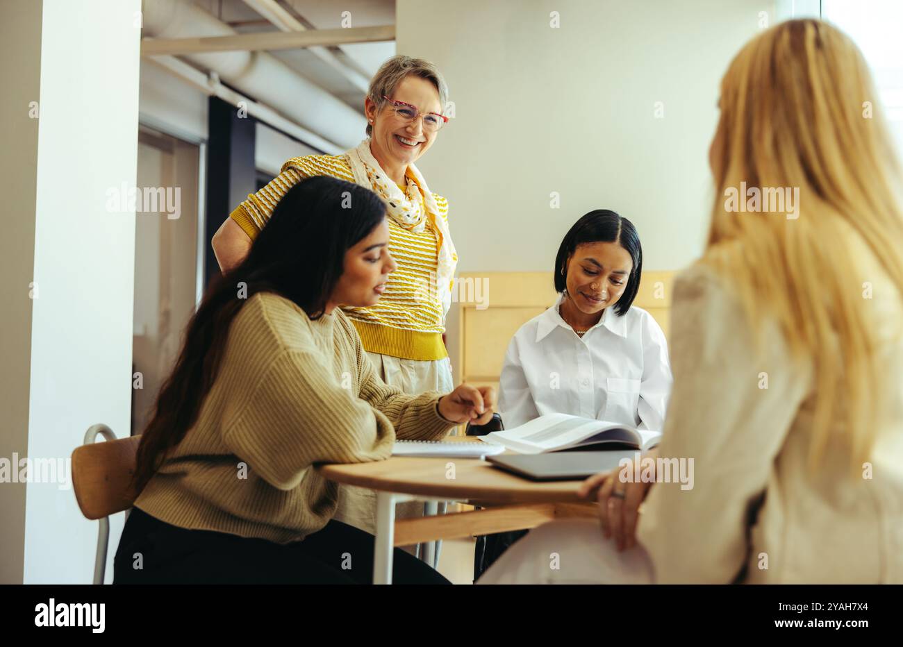 Ein fröhlicher Pädagoge interagiert mit den Schülern und fördert das Engagement und Lernen in einer warmen und kollaborativen Atmosphäre. Stockfoto