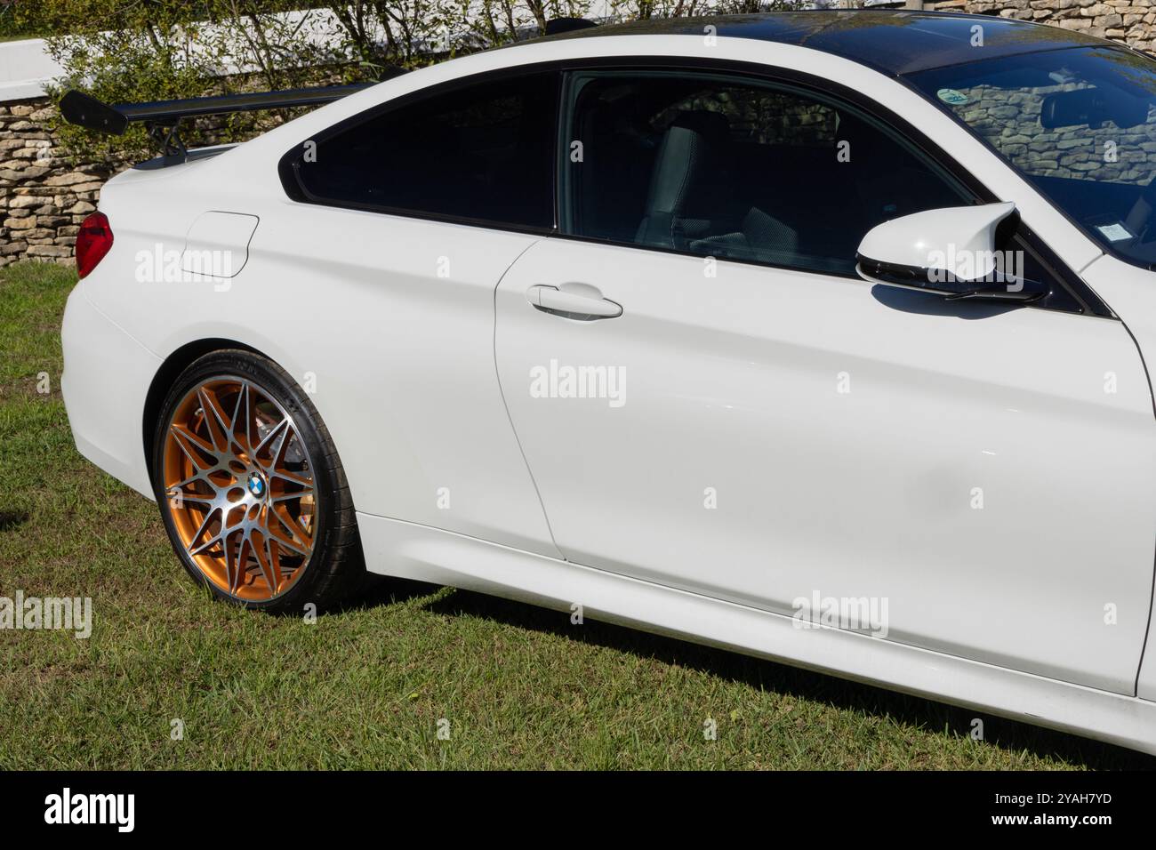 Weißer Sportwagen bmw m4 mit orangefarbenen Felgen auf grünem Gras Stockfoto