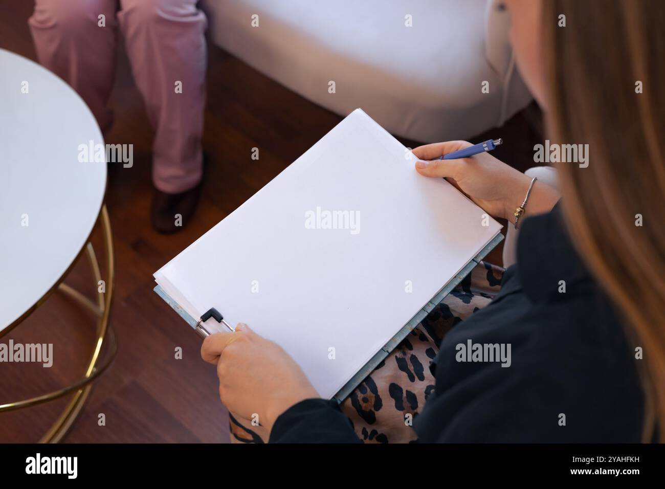 Person, die Notizen während einer Beratung in einem gemütlichen Raum mit Sitzplatz in der Nähe überprüft Stockfoto
