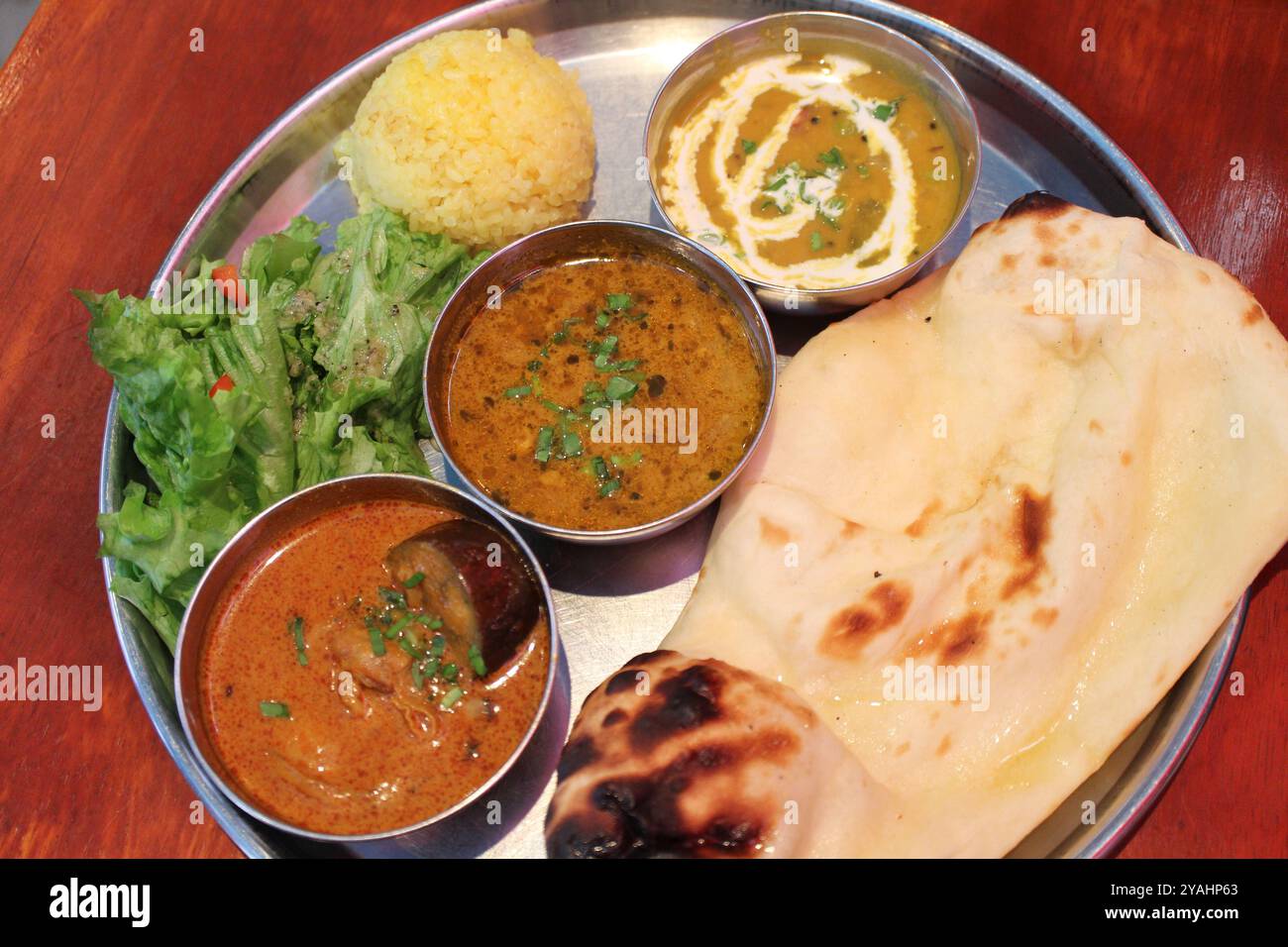 Indische Küche: Lunch-Teller mit Curry (Austern- und Auberginen-Curry, Huhn-Keema-Curry, Dal-Curry, Naan, Reis und Salat) Stockfoto