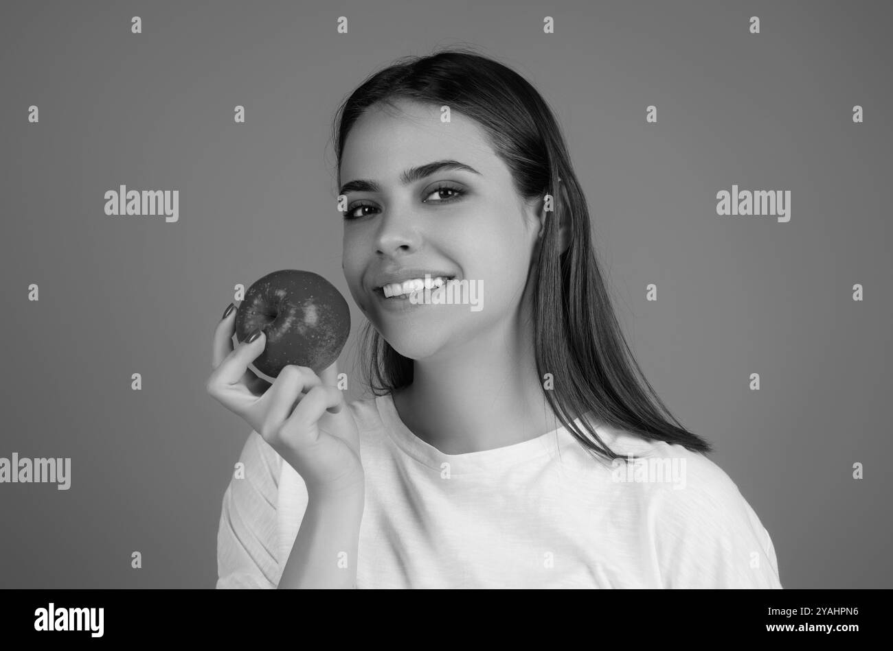 Stomatologisches Konzept. Eine Frau mit perfektem Lächeln, die einen Apfel auf einem isolierten Studio-Hintergrund hält. Die Frau isst grünen Apfel. Porträt von jungen, schönen Glücklichen Stockfoto