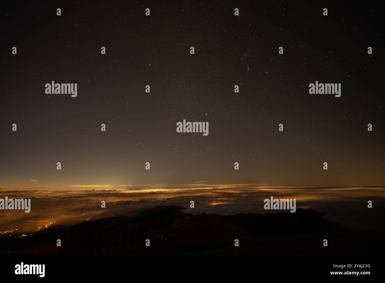 Sternenhimmel über Wolken, beleuchtet von fernen Stadtlichtern Stockfoto