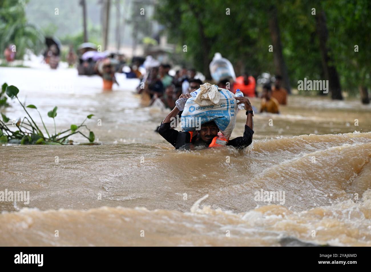 Menschen waten am 25. August 2024 durch Überschwemmungen im Bezirk Feni, Bangladesch. Stockfoto