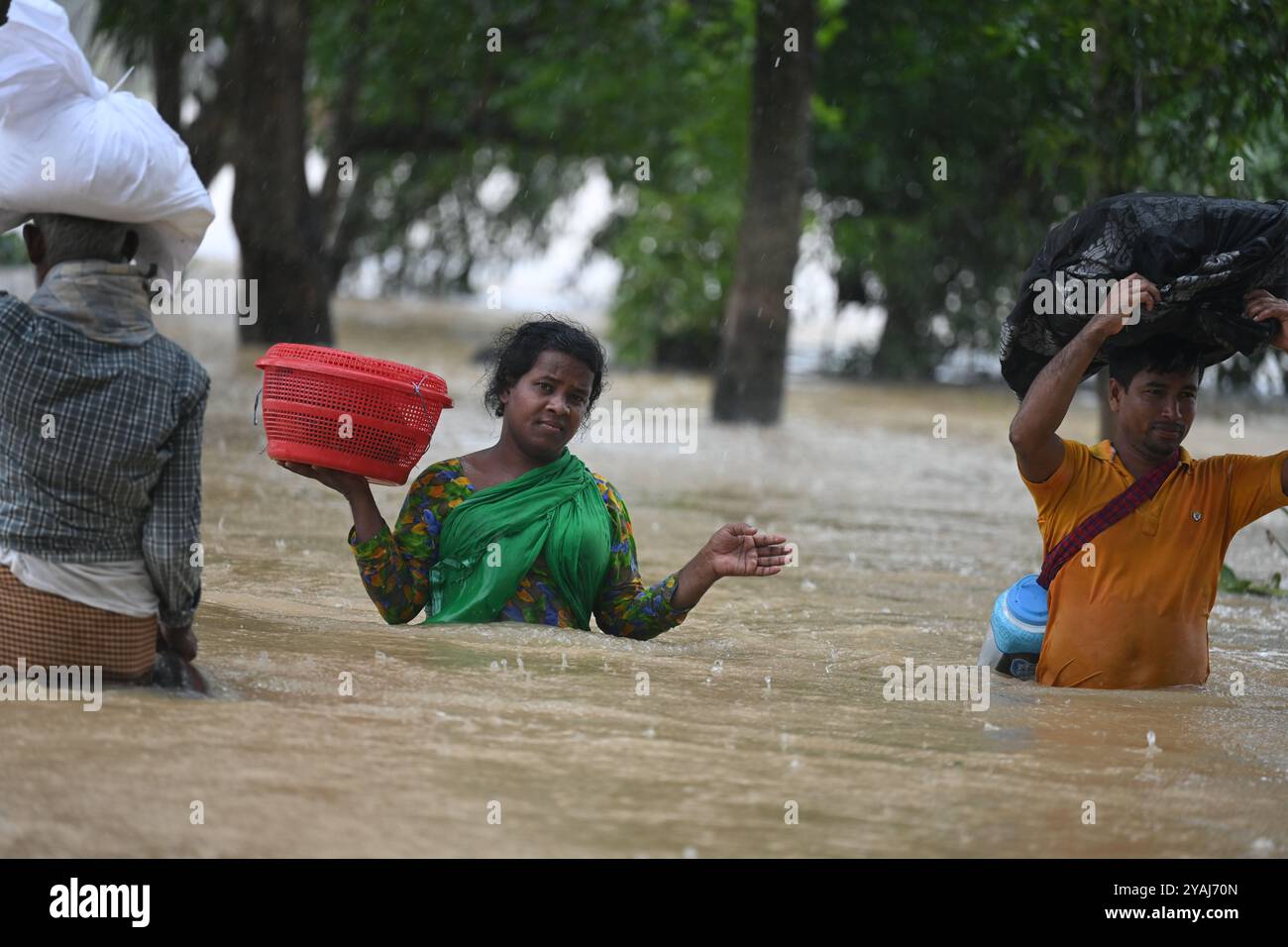 Menschen waten am 25. August 2024 durch Überschwemmungen im Bezirk Feni, Bangladesch. Stockfoto