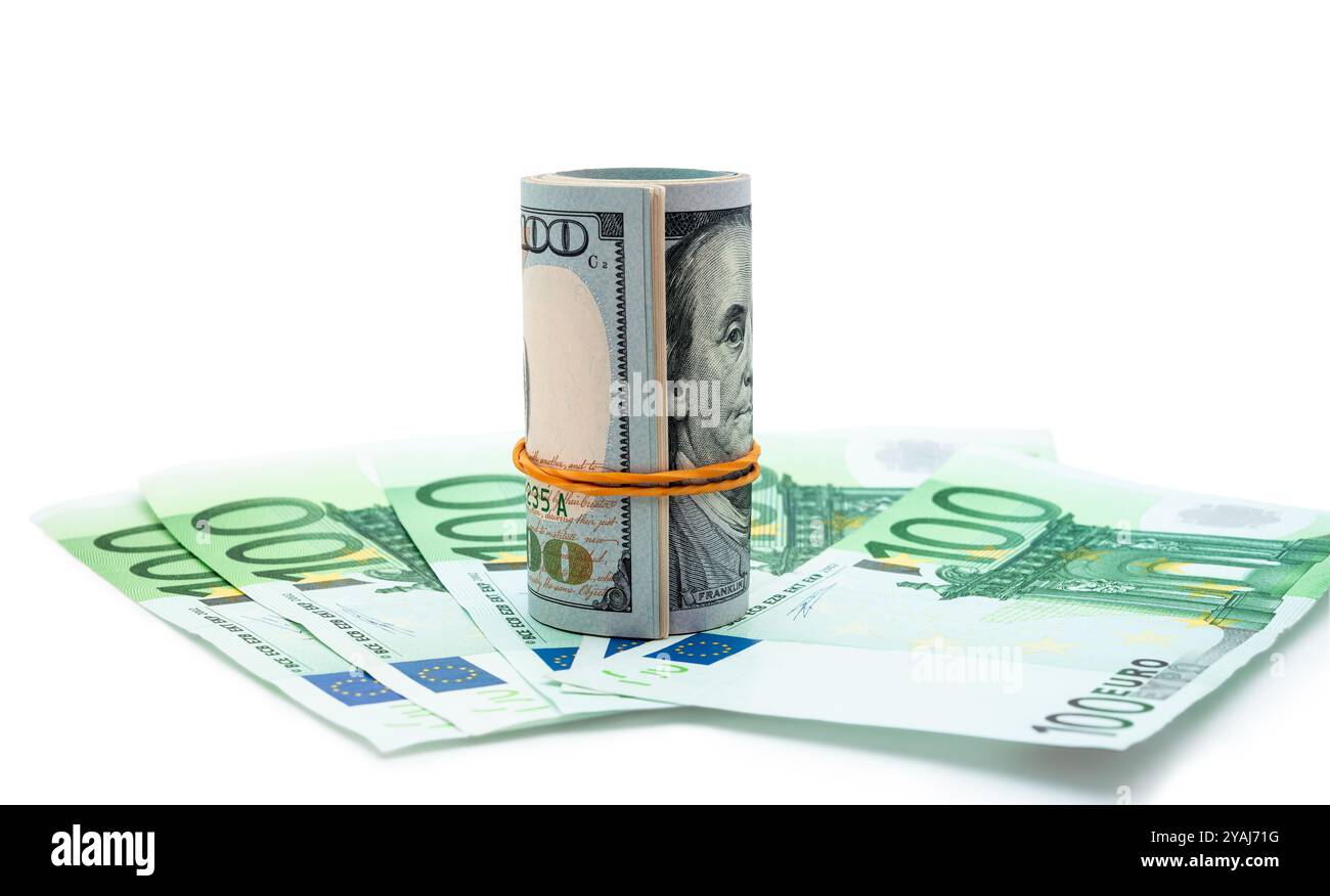 Ein gerollter Stapel von Dollars steht umgeben von aufgefächerten hundert-Euro-Scheinen, die finanzielle Vielfalt und die globale Wirtschaft symbolisieren. Stockfoto