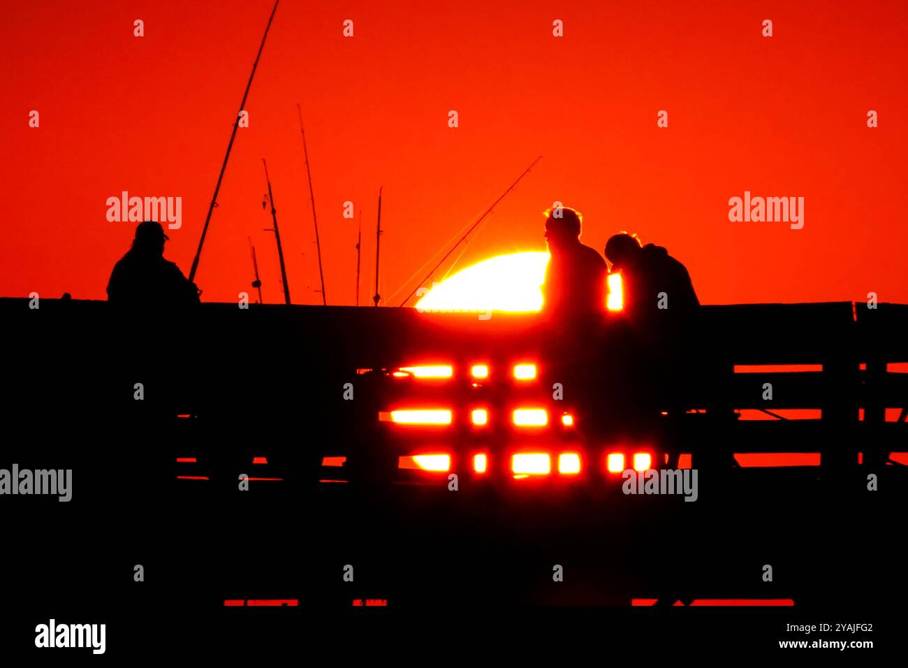 Isle Of Palms, Usa. Oktober 2024. Fisherman Silhouetten von einem dramatischen Sonnenaufgang werfen ihre Linien vor der Isle of Palms Pier am 14. Oktober 2024 in Isle of Palms, South Carolina. Klarer Himmel und warmes Wetter sind in der Prognose für das lowcountry. Quelle: Richard Ellis/Richard Ellis/Alamy Live News Stockfoto