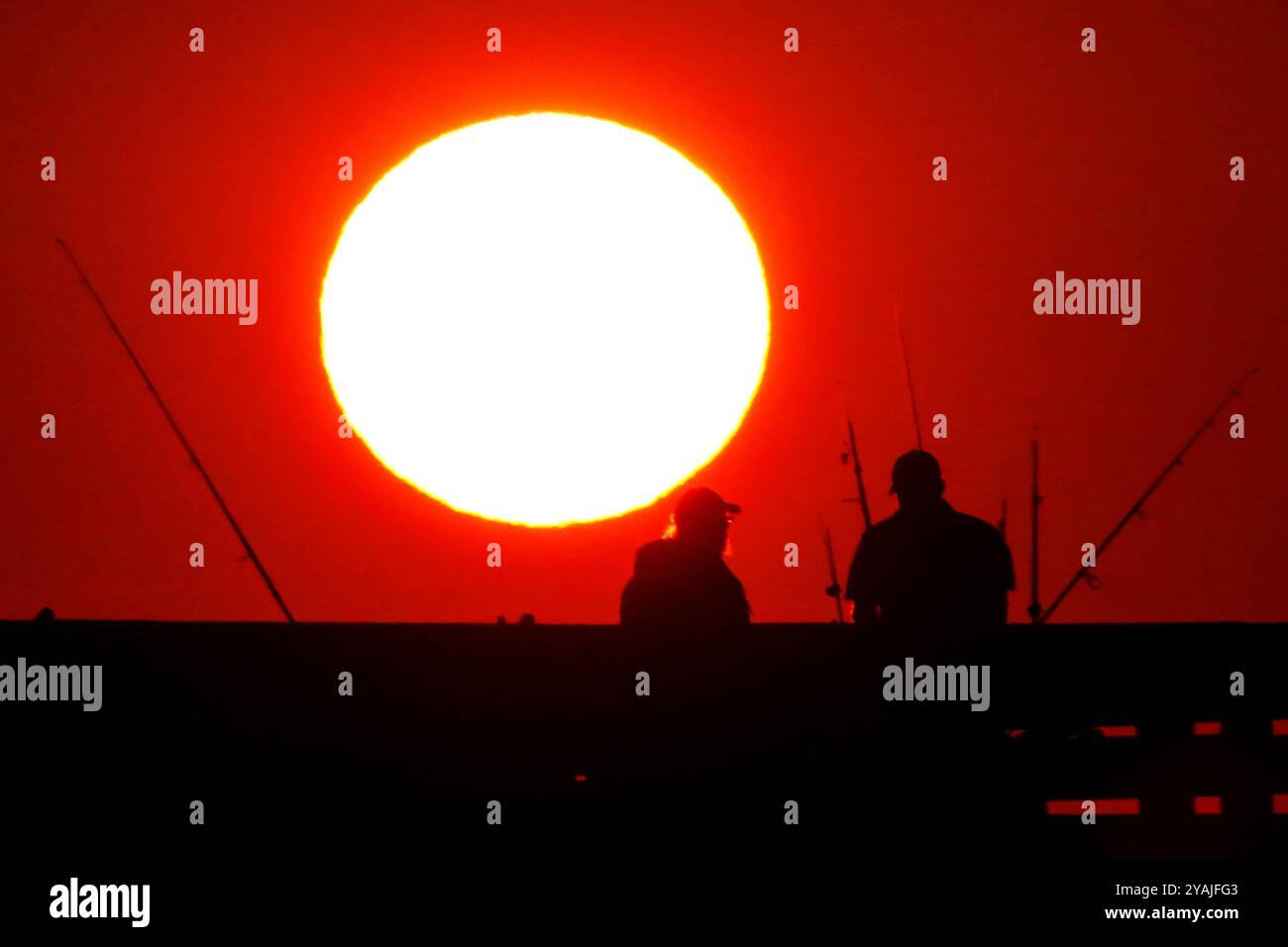 Isle Of Palms, Usa. Oktober 2024. Fisherman Silhouetten von einem dramatischen Sonnenaufgang werfen ihre Linien vor der Isle of Palms Pier am 14. Oktober 2024 in Isle of Palms, South Carolina. Klarer Himmel und warmes Wetter sind in der Prognose für das lowcountry. Quelle: Richard Ellis/Richard Ellis/Alamy Live News Stockfoto