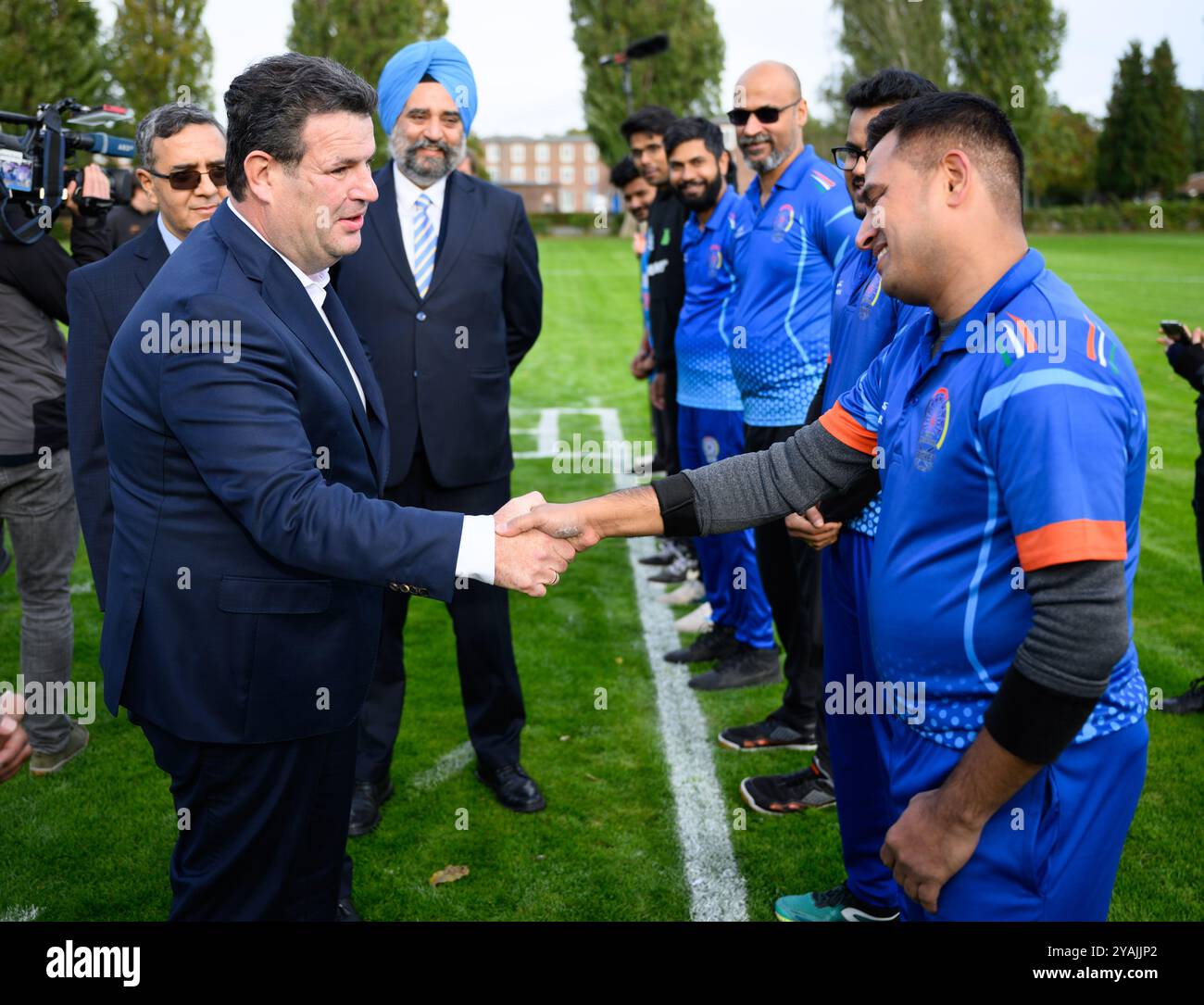 14. Oktober 2024, Berlin: Hubertus Heil (SPD), Bundesminister für Arbeit und Soziales, spricht mit Indianern über die Integration indischer Fachkräfte am Rande eines Cricketspiels im Berliner Olympiapark und begrüßt Spieler zusammen mit Ajit Gupte (l), Botschafter Indiens in Deutschland, und Madeep Singh Tuli (M), Minister der indischen Botschaft in Berlin. Anlässlich der indisch-deutschen Regierungskonsultationen am 25.10.24 trifft der Bundesarbeitsminister auf Indianer, die bereits in Deutschland leben und arbeiten: Mitglieder und Vertreter der indischen Diasporaverbände, der BER Stockfoto