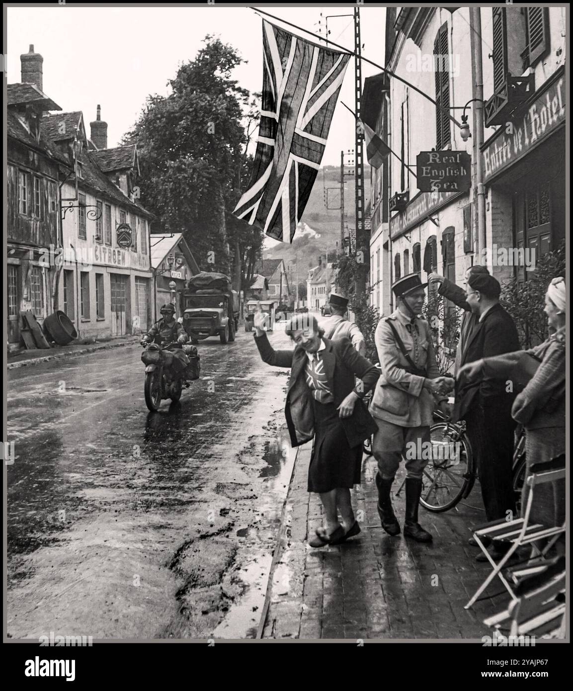 FRANKREICH BEFREIUNG NORMANDIE 2. Weltkrieg Eine Flagge der britischen Union Jack hängt in der Hauptstraße von Les Andelys in der Normandie, als die britischen Truppen am 31. August 1944 eintreffen. Die glückliche französische Dame im Vordergrund ist Madame Scarlett, Frau eines im Ausland lebenden Engländers und Besitzerin des Hotel des Fleurs, Place Saint-Sauveur. Les Andelys in der Normandie Stockfoto