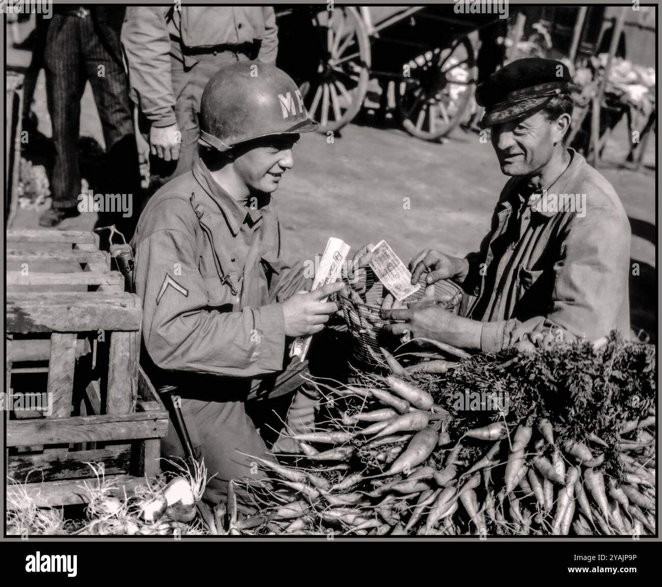 SCHLACHT UM DIE NORMANDIE nach D-DAY-Propagandabild eines amerikanischen Soldaten, der Karotten von einem französischen Bauern auf einem Markt kaufte. Mit einer „Flaggennote“ von 50 Franken, einer Währung, die im Juni 1944 von der alliierten Militärregierung der besetzten Gebiete eingeführt wurde Stockfoto