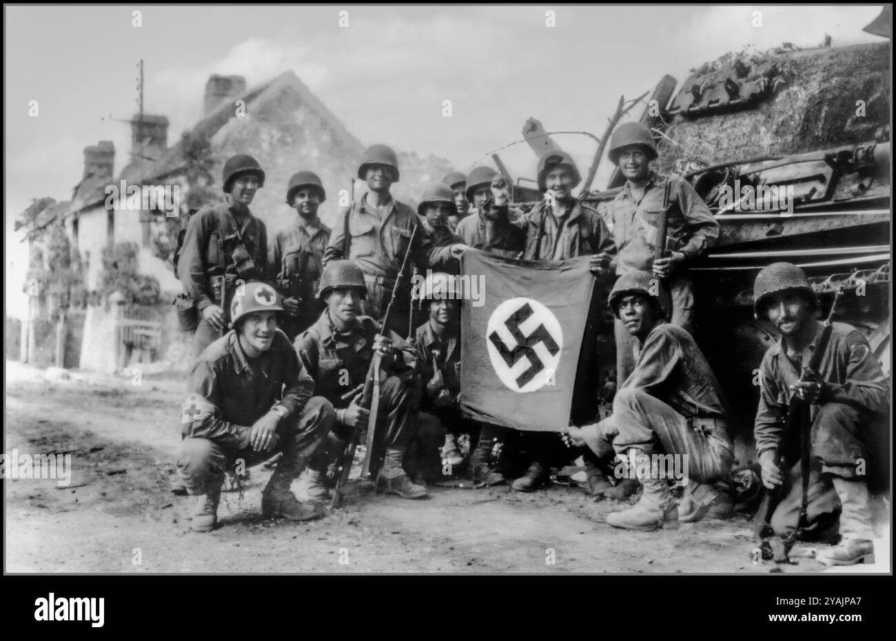 Post D-Day Gruppe von Amerikanern aus dem 359. Inf. Rgt. Der 90. US-Inf. Div Posieren Sie mit gefangenem Tank II/PZ.Rgt.16 des 116. Die Panzerdivision der Nazis hält ihre Trophäe: Eine deutsche Signalfahne mit Hakenkreuz. Normandie 1944 WW2 Nordfrankreich amerikanische Truppen feiern die Hakenkreuzfahne mit der Gefangennahme des deutschen Nazi-Panzers und des besetzten französischen Dorfes Normandie Frankreich US-Soldaten feiern mit einer gefangenen deutschen Flagge vor dem zerstörten Panther-Panzer. Die Gruppe der Infanteristen wurde zurückgelassen, um in Chambois, Frankreich, der letzten Hochburg der Deutschen in der Falaise Gap Normandie, Frankreich, zu "aufräumen" Stockfoto