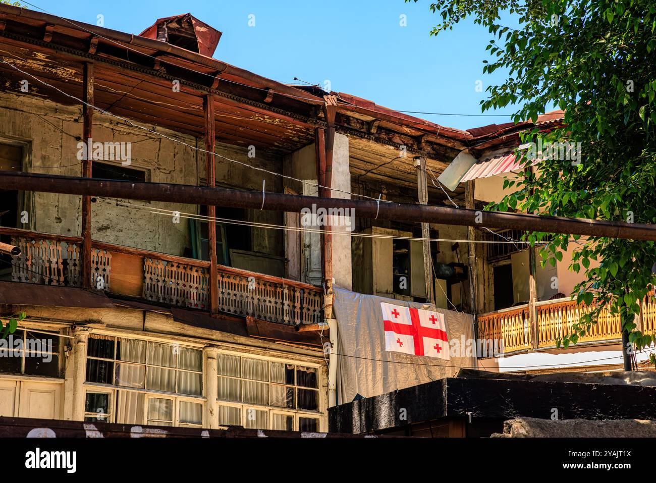 Typischer Innenhof der heruntergekommenen Häuser des alten tiflis mit Balkonen und Wäscheleinen des alten tiflis und der georgischen Flagge Stockfoto