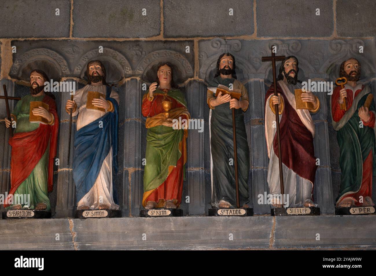 Sechs von 12 polychromen Apostelstatuen, die 1721 in Holz gemeißelt wurden und den Eingang einer bretonischen Kirche, L’Eglise Saint Sauveur, in Le Faou, Finistère, Bretagne, flankieren. Frankreich. Die Namen der Apostel sind auf den Sockeln unter ihren Füßen in bretonischer Sprache handgemalt. Die Statuen wurden kürzlich restauriert und neu gestrichen. Stockfoto