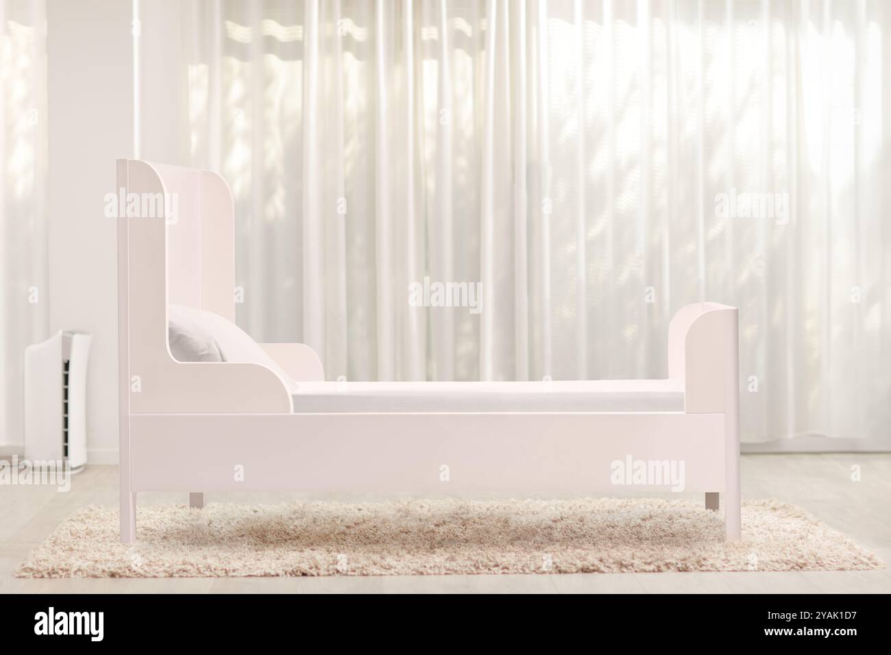 Weißes leeres Bett für Kinder in einem Zimmer auf einem Teppich Stockfoto