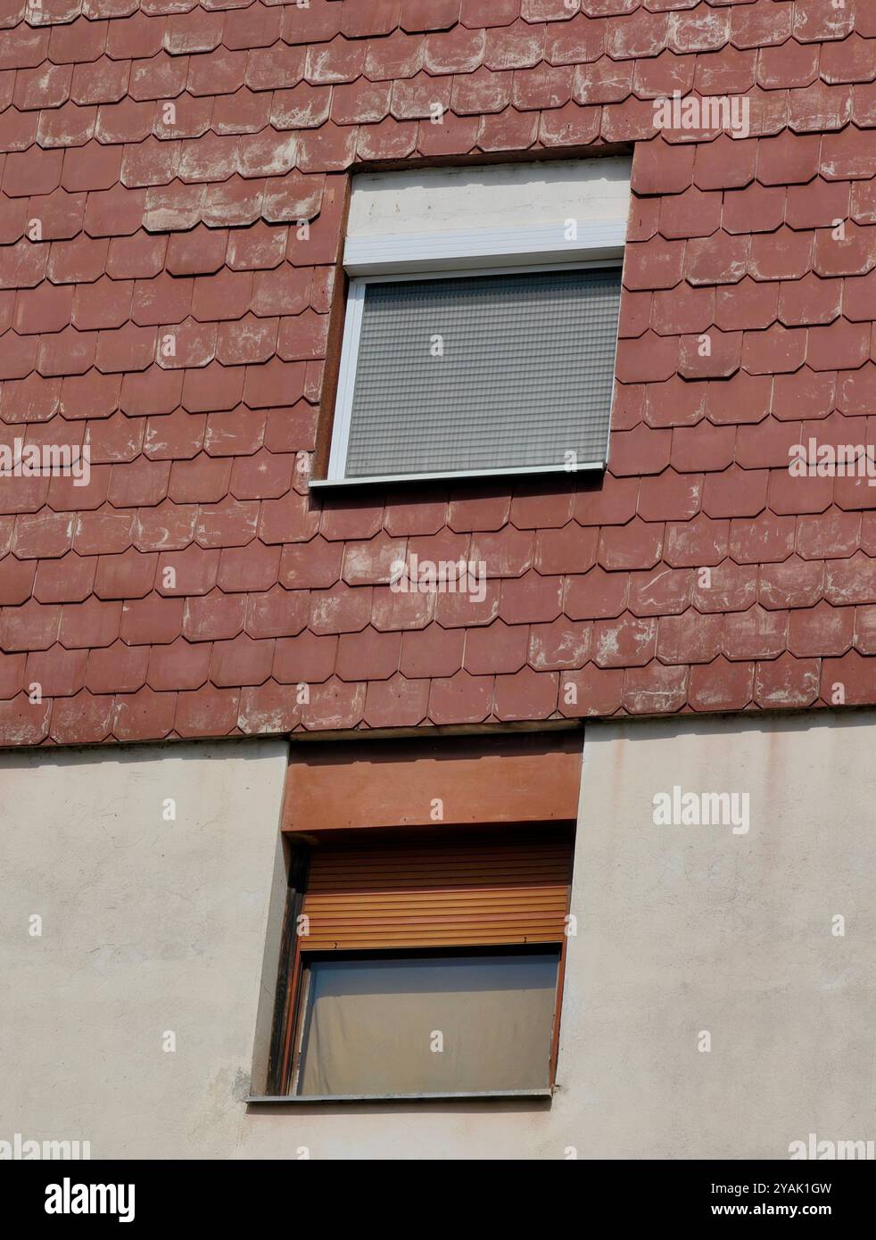 Zwei Fensterrahmen mit kontrastierenden Jalousien und roten Dächern Stockfoto