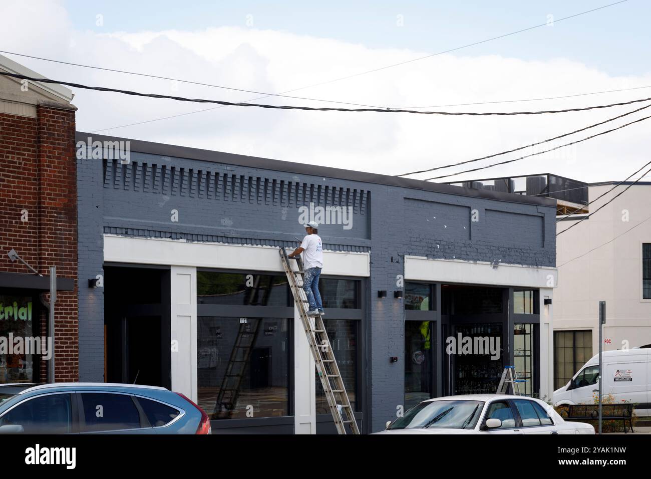 Knoxville, TN, USA – September 18. 2024: Ein Hausmaler, der in Happy Holler arbeitete, malte von einer Erweiterungsleiter aus in Happy Holler in North Central. Stockfoto