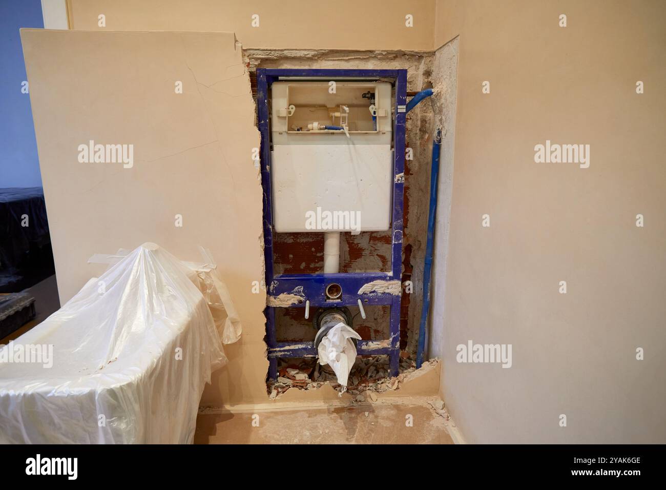 Wand im Bau, die die innere Zisterne eines Badezimmers in einem Haus zeigt, dessen Bidet zum Schutz mit Kunststoff bedeckt ist Stockfoto
