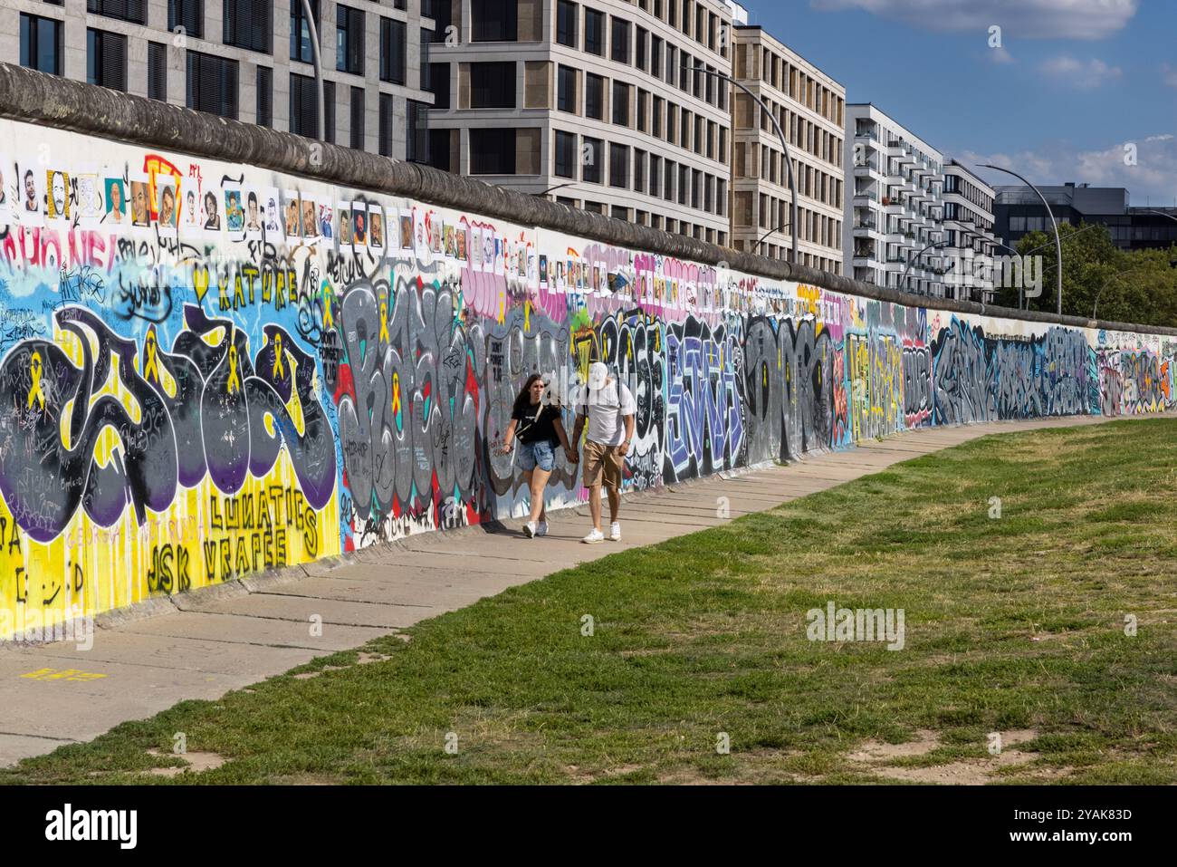 Die Menschen laufen auf der Rückseite der East Side Gallery, Teil der Berliner Mauer in Friedrichshain, Berlin, Deutschland Stockfoto