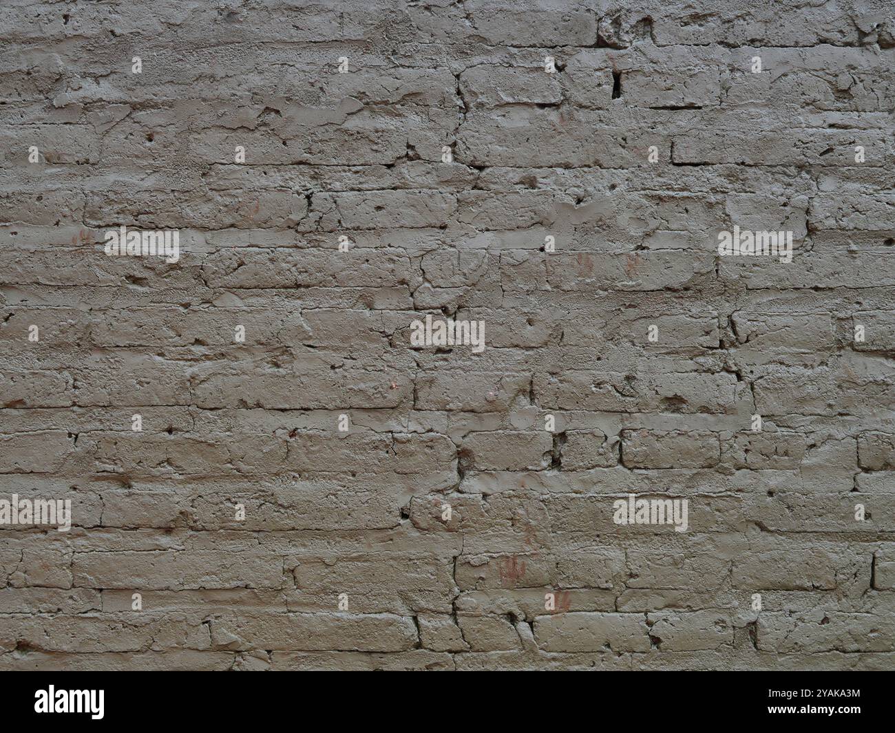 Alte Ziegelmauer mit sichtbaren Rissen in grauer Farbe, verwittertem Mauerwerk und historischen architektonischen Details Stockfoto