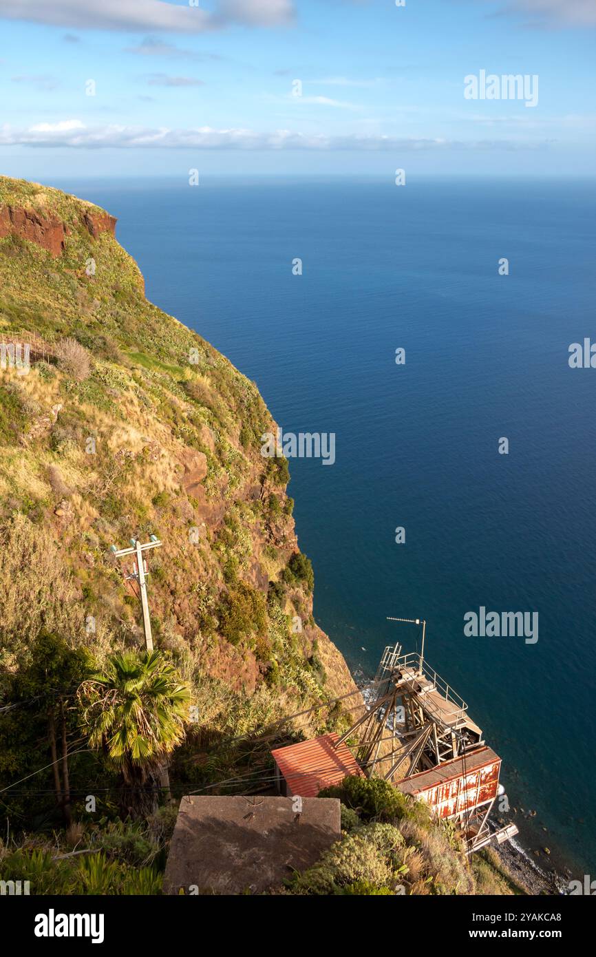 Blick vom Berg auf eine von Grün und Atlantik bedeckte Klippe. Blauer Himmel mit hellweißen Wolken im Frühling. Faja dos Padres, Madei Stockfoto