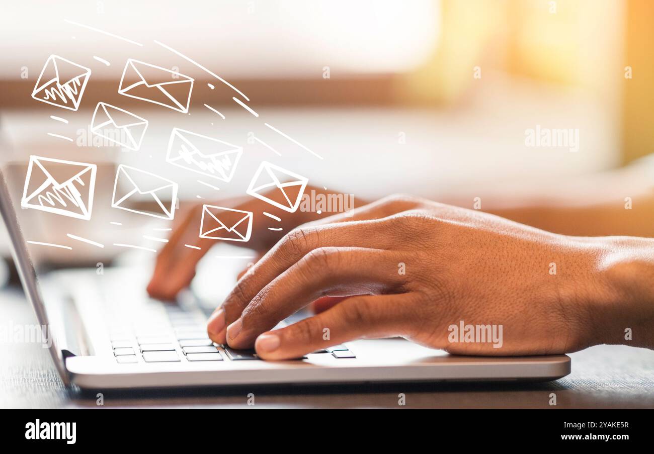 Online-Kommunikation. Afroamerikanischer Mann, der im Büro E-Mails schreibt und sendet, mit Umschlagsymbolen gestaltet Stockfoto