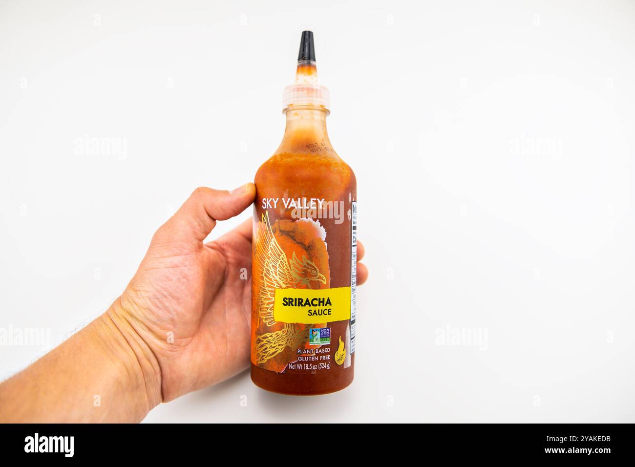 Avon, USA - 4. August 2022: Sriracha-Sauce heiße Thai-Chili-Paprika Würzmittel in Plastikflasche, Hand auf weißem Hintergrund halten Stockfoto