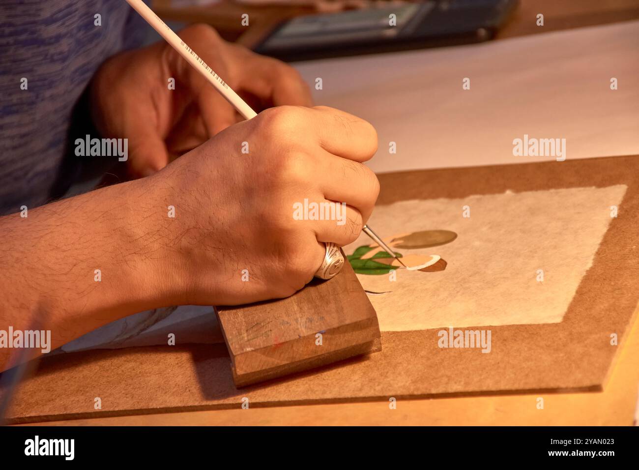 Dieses fesselnde Bild zeigt die geschickten Hände einer handwerklichen Holzmalerei auf einem der pulsierenden Basare von Buchara, Usbekistan. Bekannt für sein reiches Cu Stockfoto