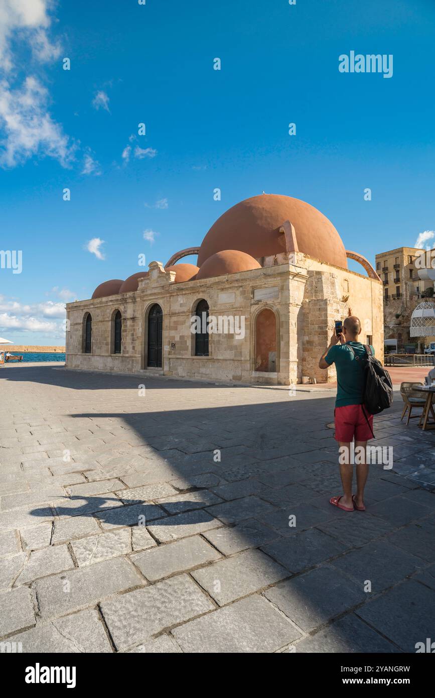 Der Mann allein reist, Rückansicht eines Mannes, der ein Foto der Kucuk Hasan Pascha Moschee im Hafen der Altstadt von Chania (Hania) auf Kreta, Griechenland, macht Stockfoto