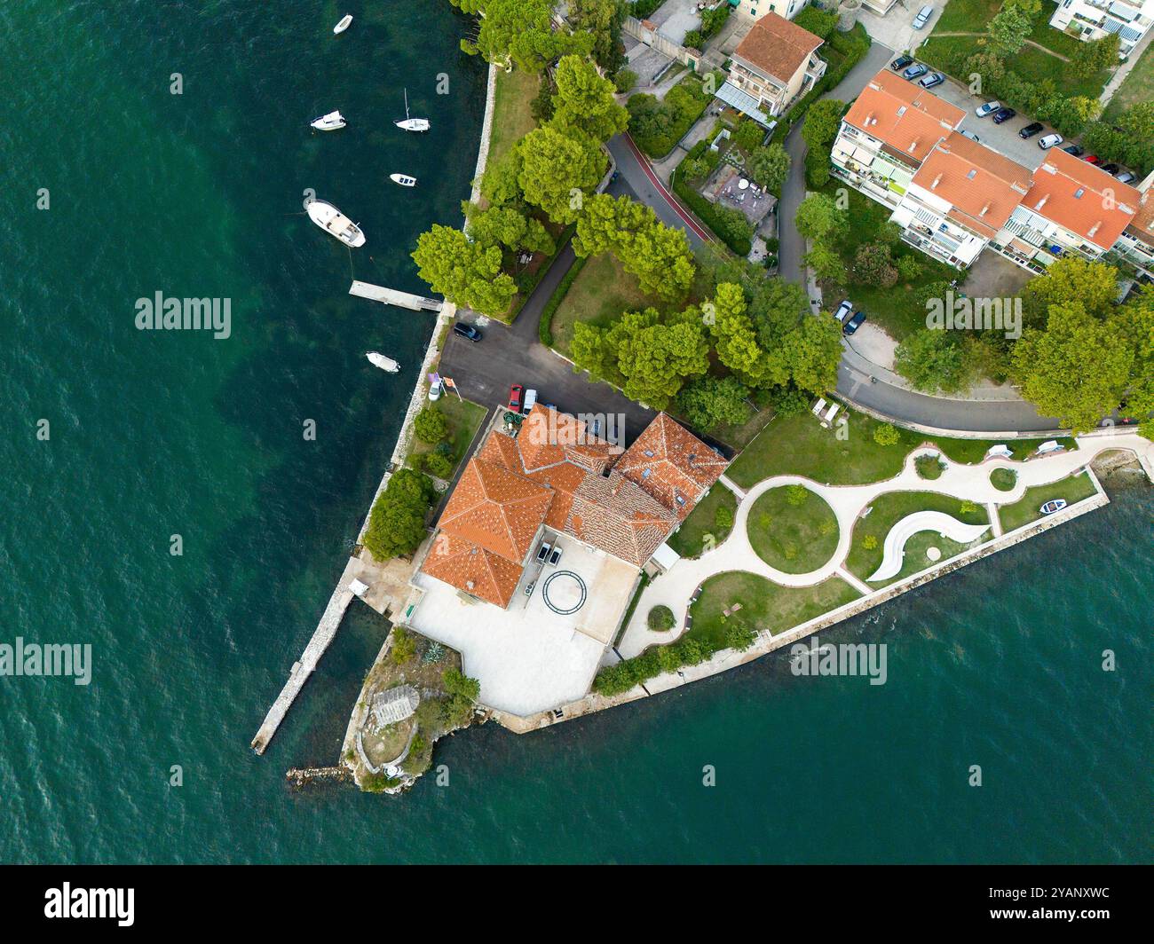 Ein Damm, der ins Meer ragt, mit Häusern, Parkplätzen und geparkten Booten. Luftaufnahme Stockfoto
