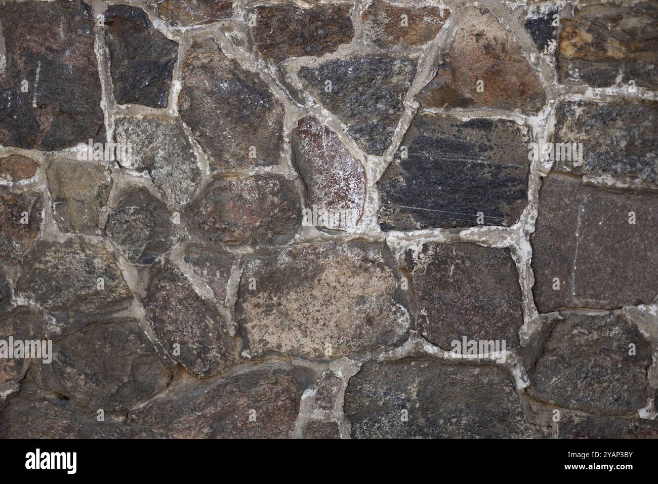 Nahaufnahme einer Natursteinmauer mit strukturierter Oberfläche an einem sonnigen Tag. Konzept der Architektur, Baumaterialien und rustikalen Außenhintergründe Stockfoto