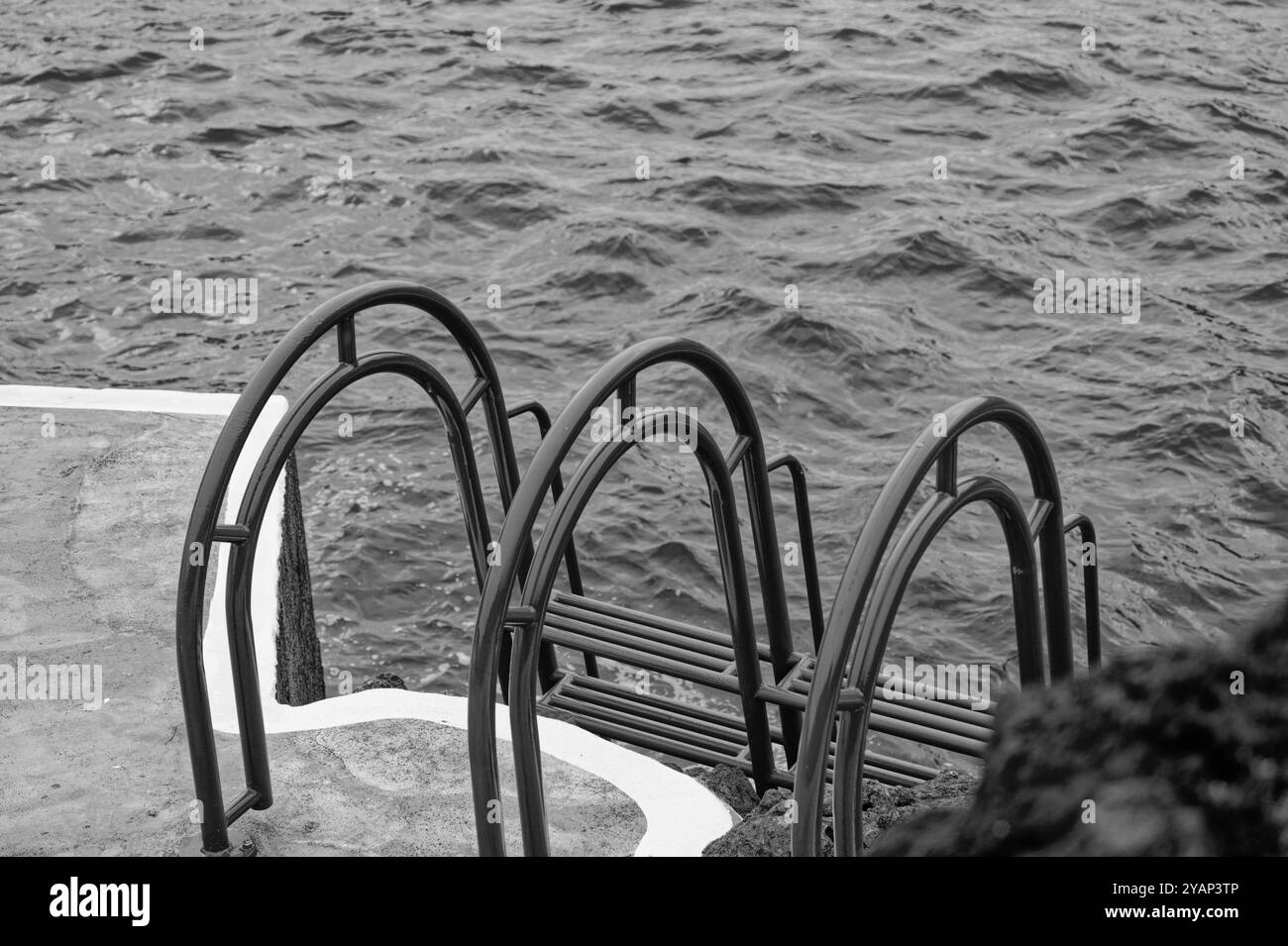Monochrom einer Leiter, die in das aufgewühlte Meer in den natürlichen Pools von Porto Moniz führt Stockfoto
