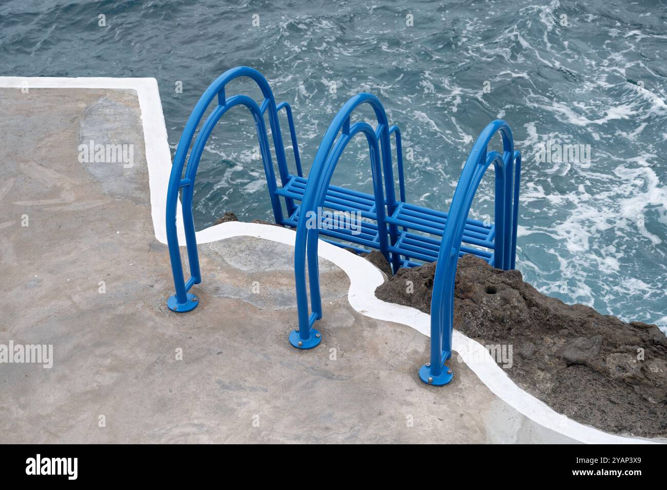 Die hellblaue Leiter führt in das aufgewühlte Meereswasser der natürlichen Pools von Porto Moniz Stockfoto