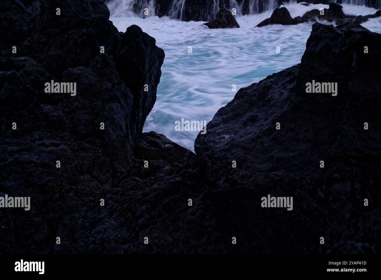 Ein Blick auf das wirbelnde Meer, das von dunklen vulkanischen Felsen eingerahmt wird, in den natürlichen Pools von Porto Moniz Stockfoto