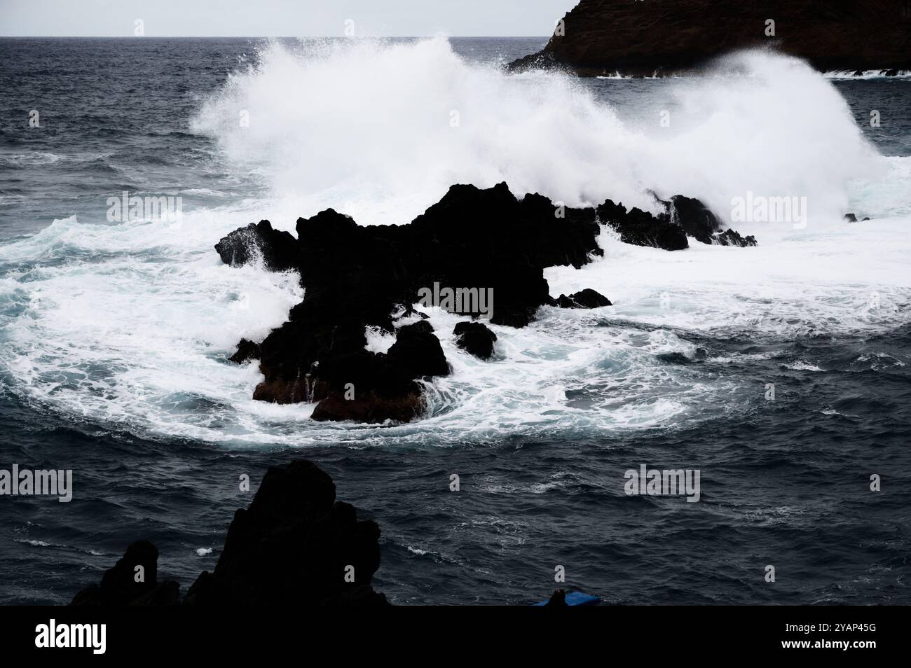 Wellen schlagen heftig gegen die dunklen vulkanischen Felsen von Porto Moniz Stockfoto