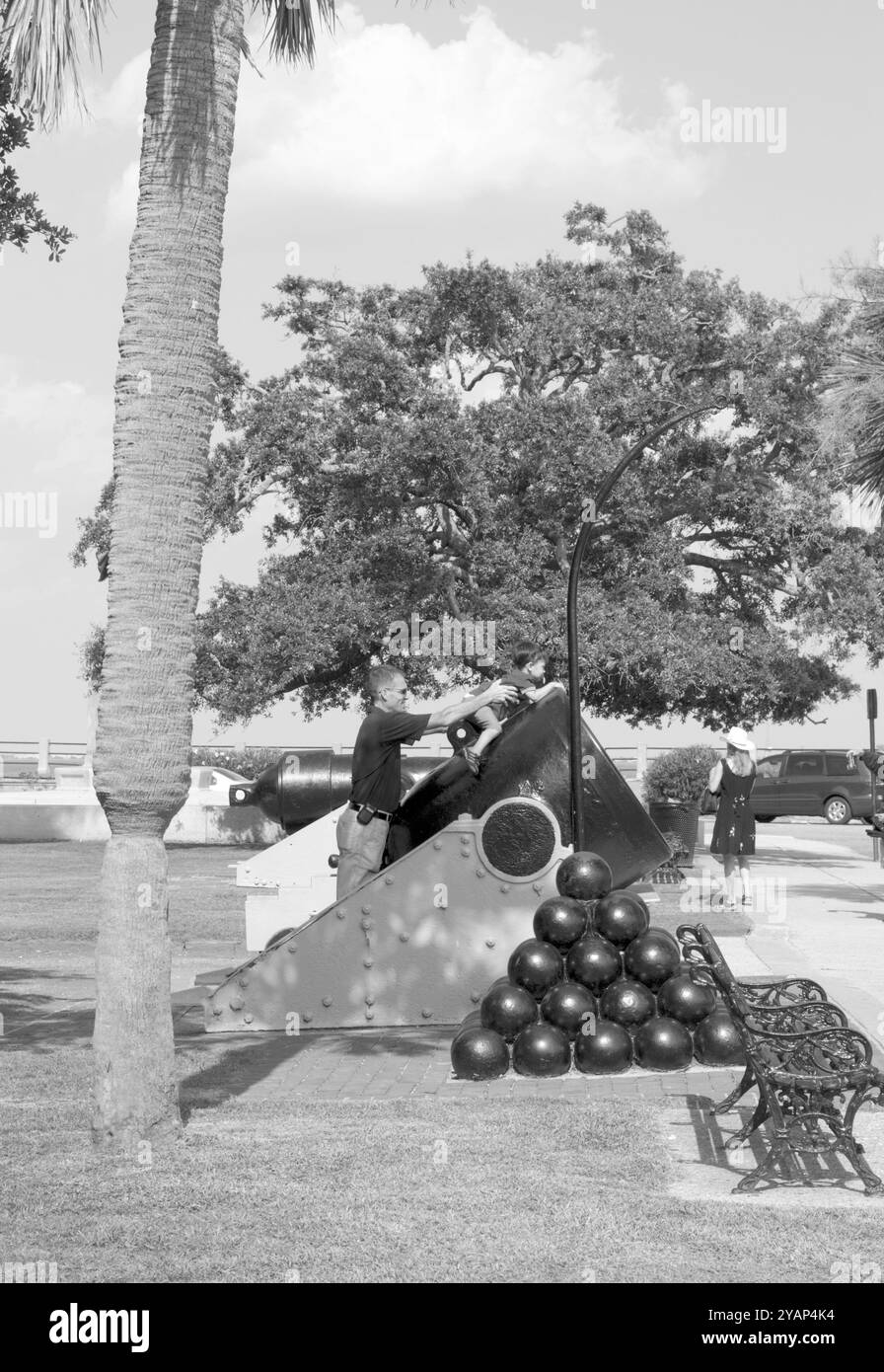 Kaukasischer Vater und kleiner Sohn spielen auf einer historischen Kanone im Battery Park in Charleston, South Carolina, USA. Stockfoto