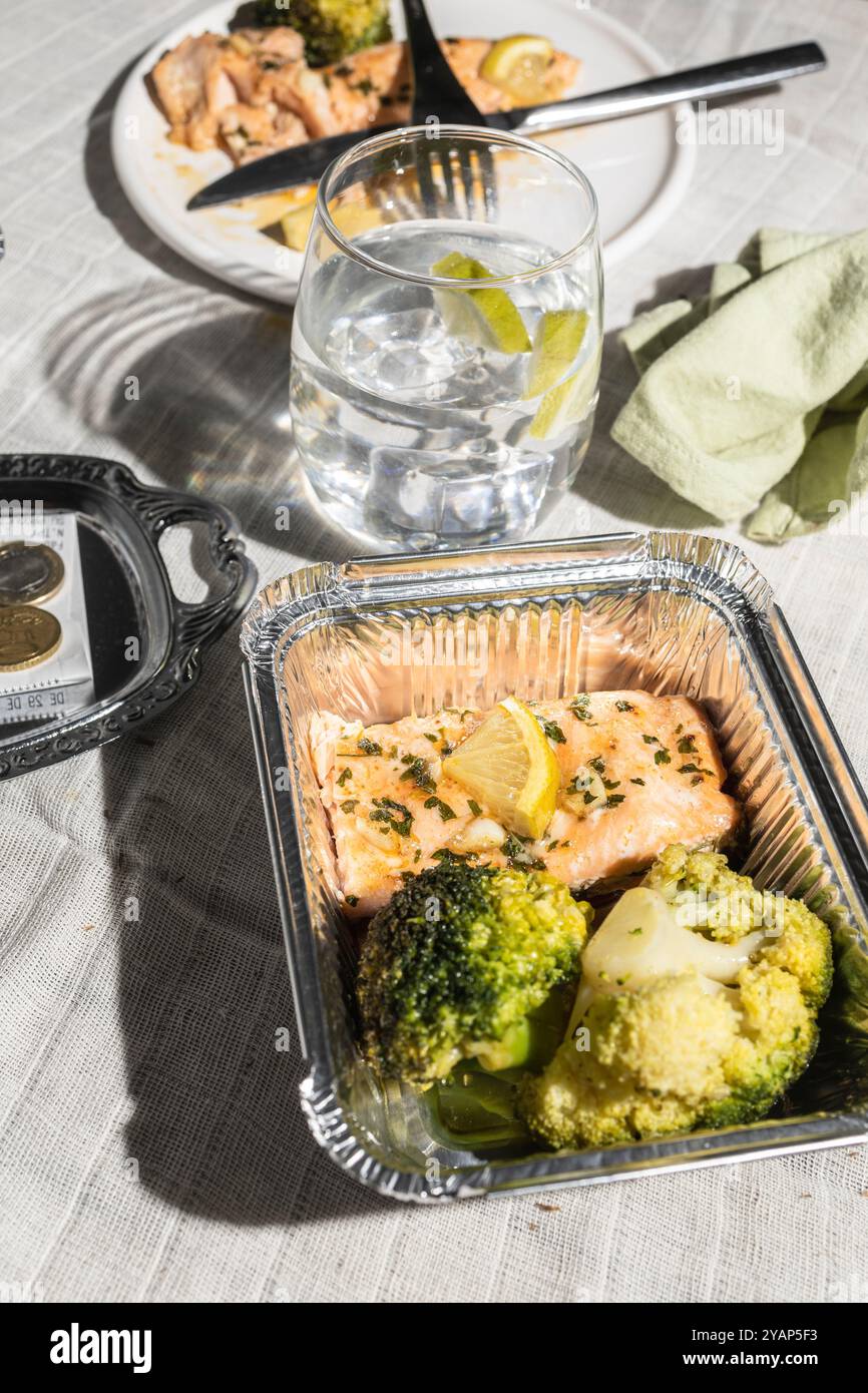 Blick von oben auf einen Restauranttisch nach dem Essen, mit gebackenen Lachsresten, die in einem Hundebeutel verpackt werden können, was zu Null Abfall und Repurposin für Lebensmittel beiträgt Stockfoto