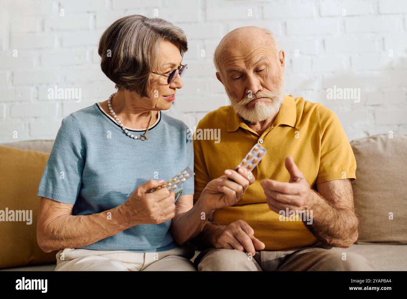 Eine fürsorgliche Frau hilft ihrem Mann, seine Diabetes-Medikamente zu überprüfen, während sie zusammen sitzt. Stockfoto