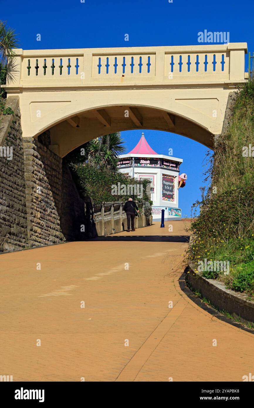 Brücke überquert Pfad zum Strand, mit einem Eisstand in der Ferne, Whitmore Bay, Barry Island, Vale of Glamorgan, Südwales, UK. Stockfoto