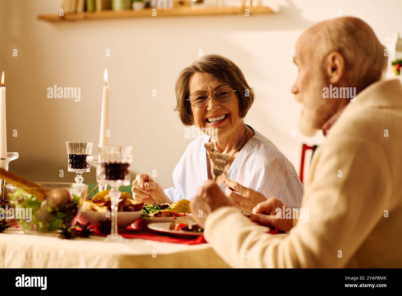 Ein fröhliches Seniorenpaar genießt ein festliches Weihnachtsessen zu Hause. Stockfoto