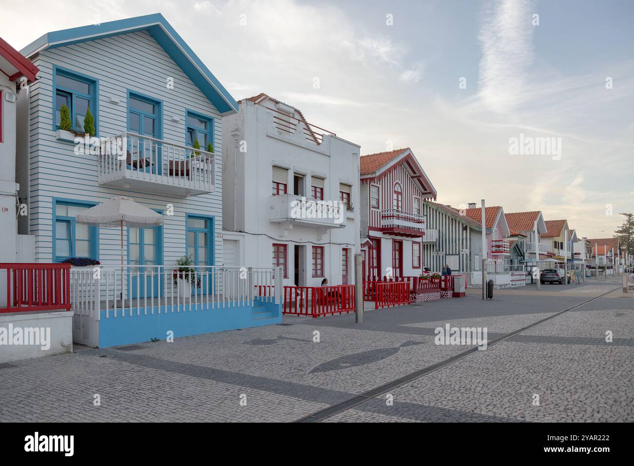 Portugiesische Touristenstraße mit ihren emblematischen gestreiften und farbenfrohen Häusern. Ende des Tages. Costa Nova do Prado, Aveiro, Portugal - August 2024 Stockfoto