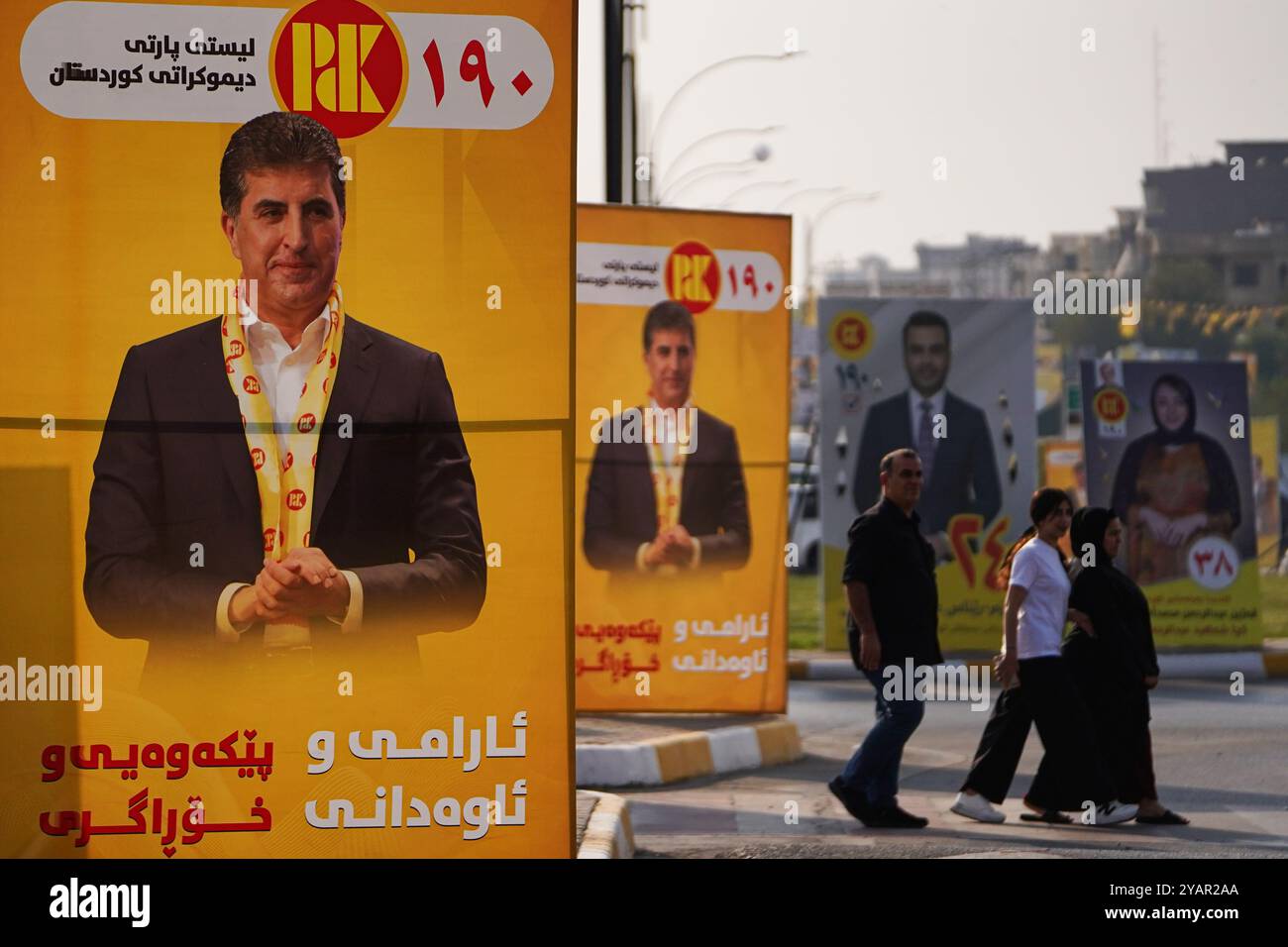 Duhok, Irak. Oktober 2024. Die Menschen gehen an Wahlbändern der Kandidaten der Kurdischen Demokratischen Partei (KDP/PDK) und anderen vorbei, die Bilder des Vizepräsidenten der Partei Nechirvan Barzani vor den Wahlen zum Kurdischen Regionalparlament in Duhok, Irak, tragen. (Credit Image: © Ismael Adnan/SOPA Images via ZUMA Press Wire) NUR REDAKTIONELLE VERWENDUNG! Nicht für kommerzielle ZWECKE! Stockfoto