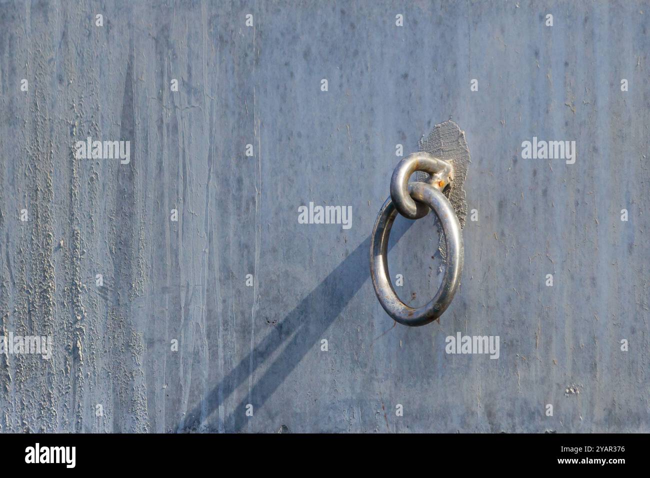 Ein geschlossener Edelstahlhaken und sein Schatten an der Wand Stockfoto