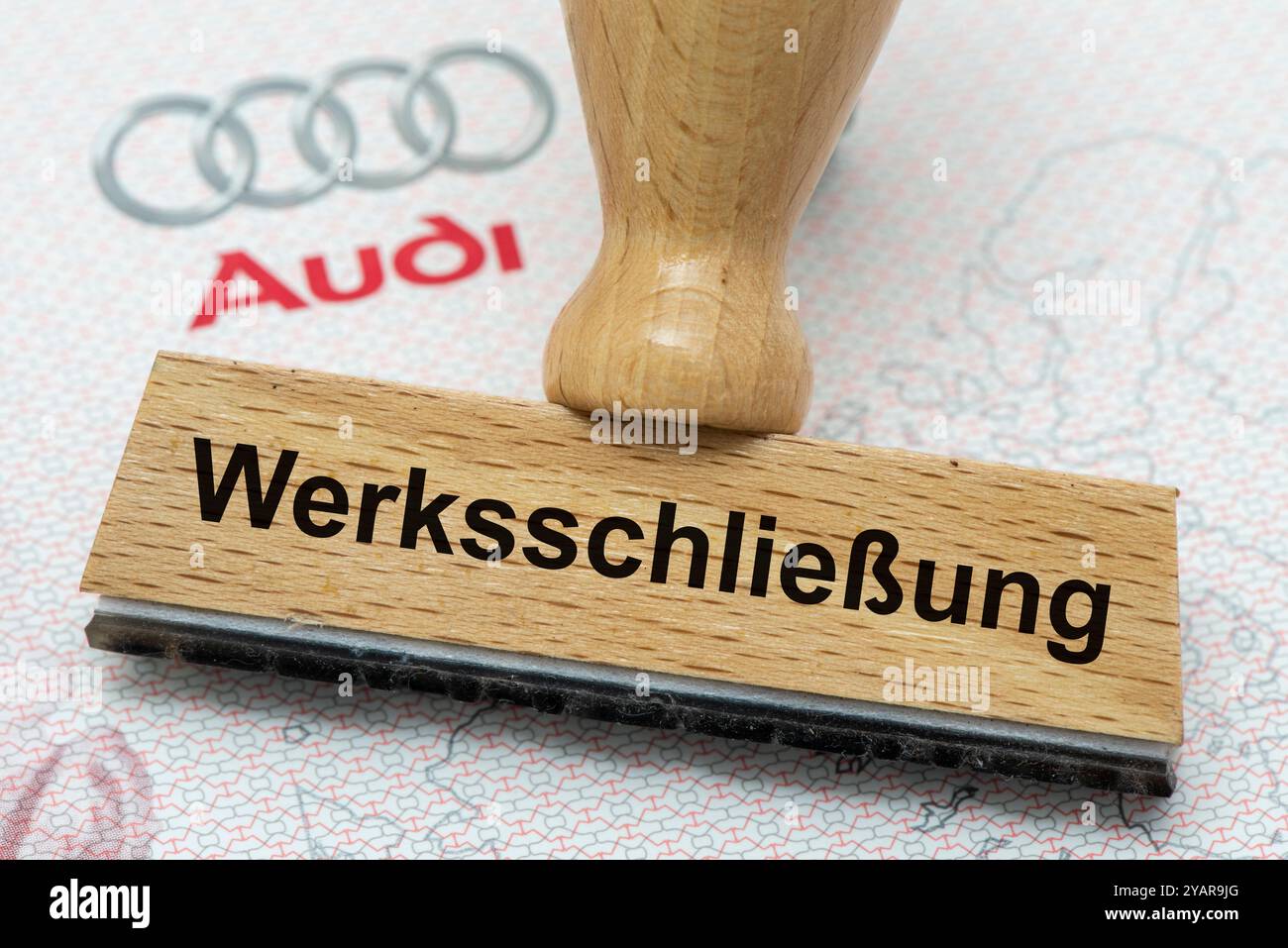 AUDI-Krise mit Gefahr der Werksschließung ein Holzstempel ist beschriftet mit dem Aufdruck: Werksschließung, über einer AUDI-Aktie - Symbolbild *** AUDI-Krise mit Gefahr der Werksschließung Ein Holzstempel ist beschriftet mit dem Aufdruck: Werksschließung, über einer AUDI-Aktie symbolisches Bild Stockfoto