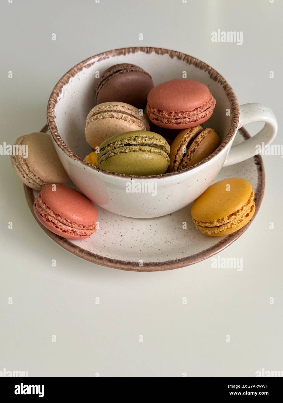Macarons in verschiedenen Farben und Geschmacksrichtungen im weißen Becher - Smartphone-aufgenommenes Stockfoto