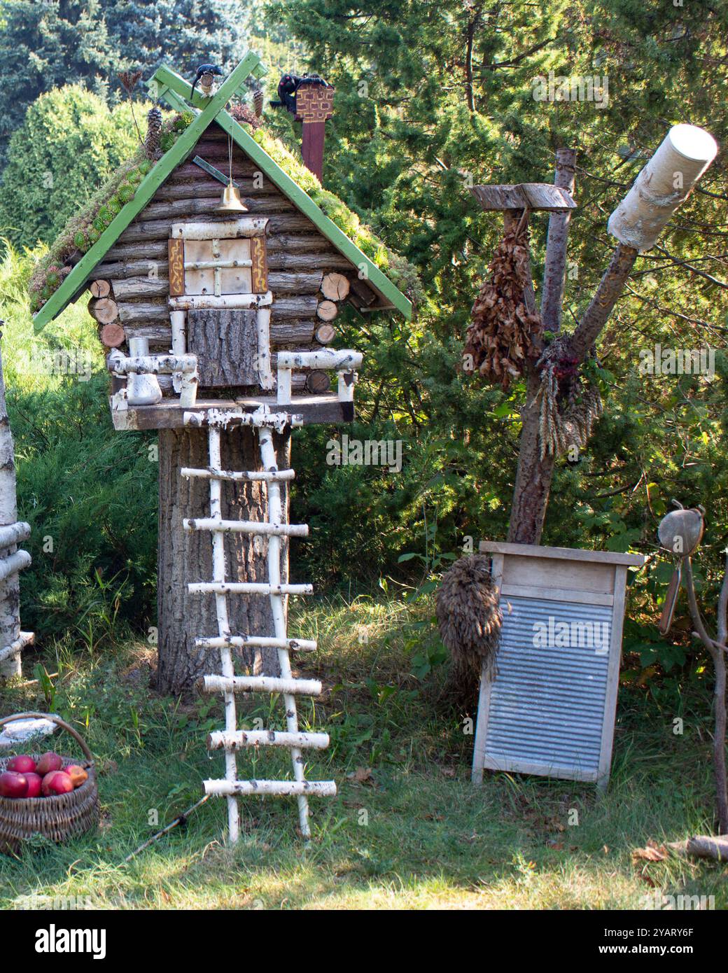 Märchenhaus aus Holzstämmen mit einer Leiter aus Birkenstämmen. Neben dem Haus gibt es ein Waschbrett, einen Besen und einen Korb mit Äpfeln. T Stockfoto