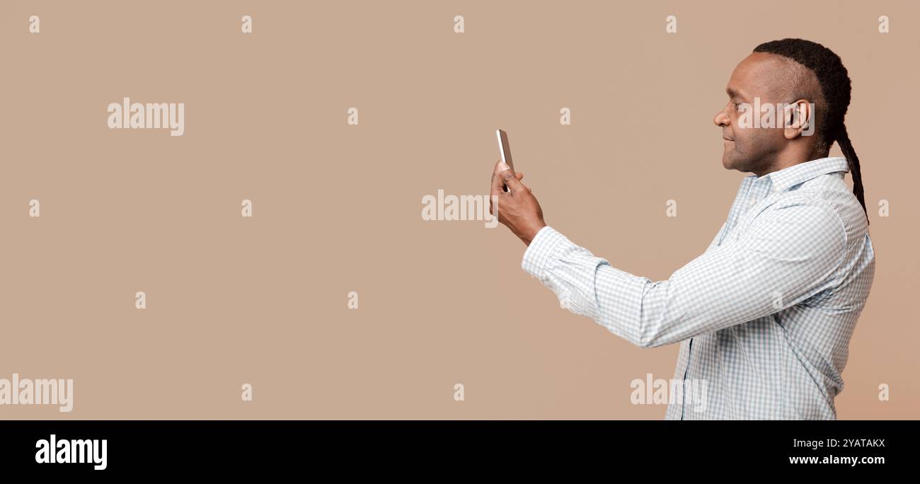 Mann im mittleren Alter, der sein Gesicht auf dem Handy abtastet Stockfoto