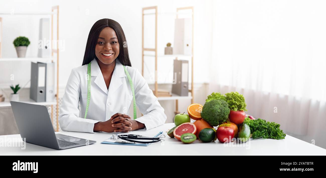 Lächelnder Ernährungsberater mit Gemüse und Obst im Büro Stockfoto