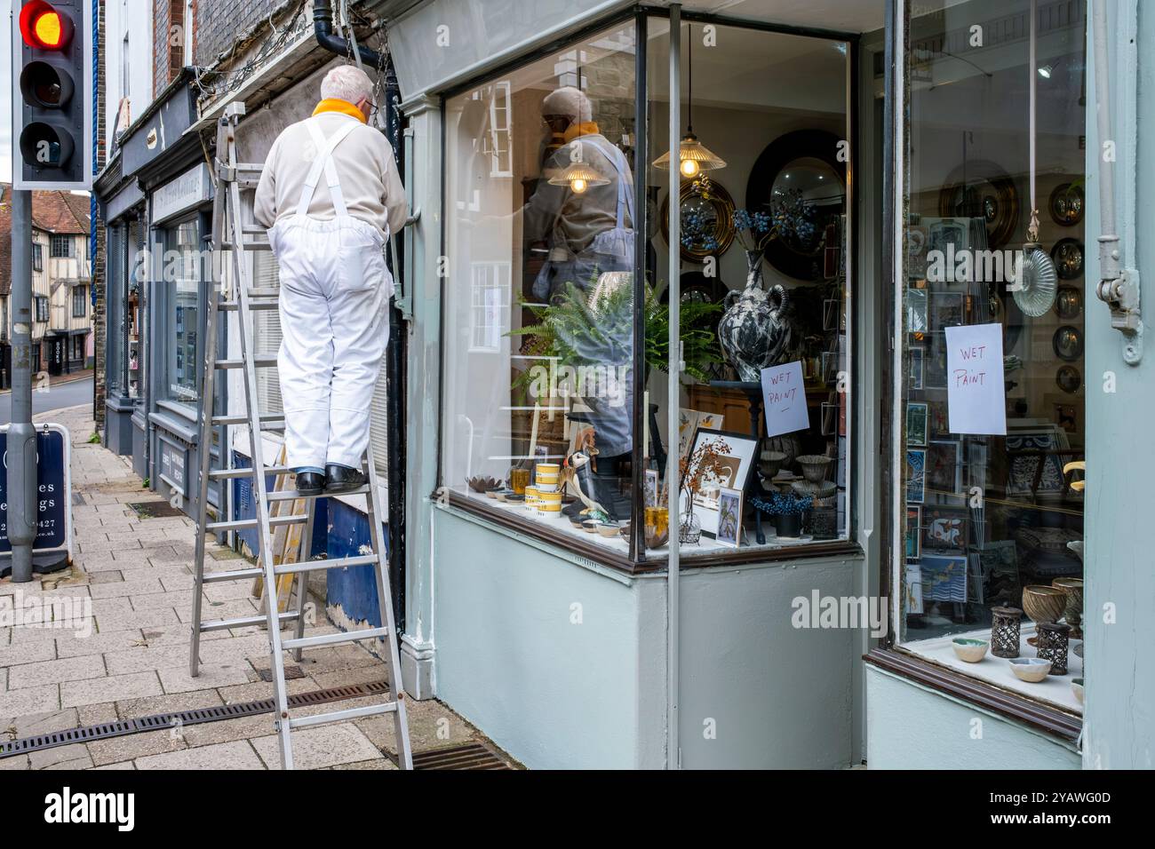 Ein Senior Mann, der Einen Außenbereich Eines Ladens malte und dekorierte, High Street, Lewes, East Sussex, Großbritannien. Stockfoto