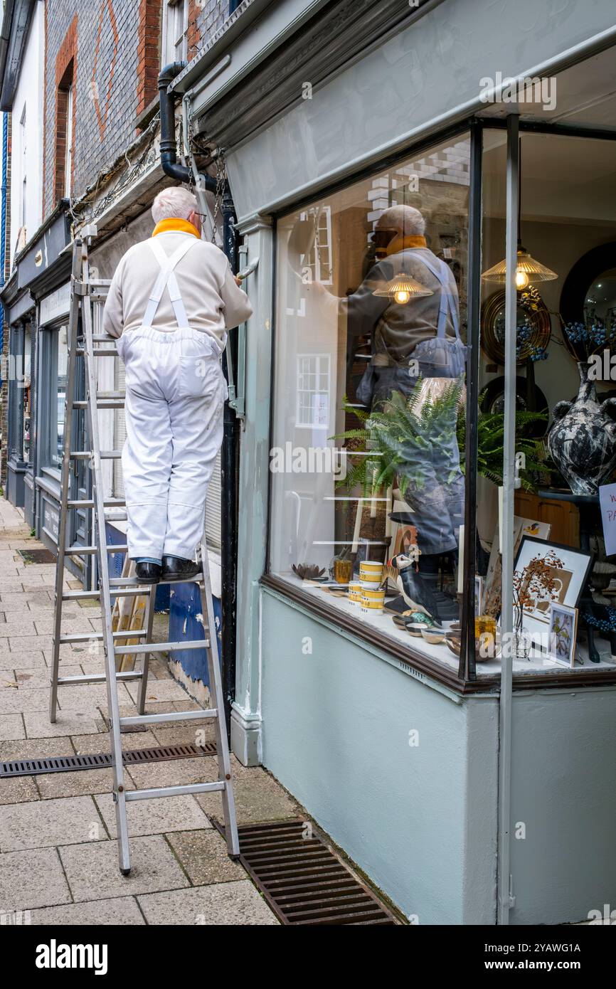 Ein Senior Mann, der Einen Außenbereich Eines Ladens malte und dekorierte, High Street, Lewes, East Sussex, Großbritannien. Stockfoto