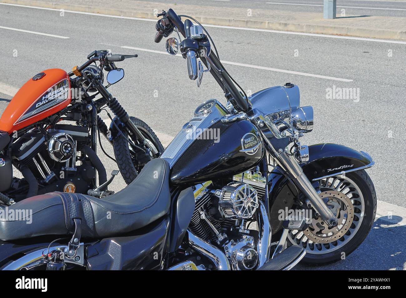 Zwei geparkte harley davidson-Motorräder, ein softail und eine achtundvierzig, die im Sonnenlicht leuchten Stockfoto